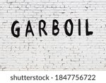 Small photo of Inscription garboil written with black paint on white brick wall.