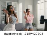 Asian young woman with her friend tiktoker created her dancing video by smartphone camera together. To share video on social media application 