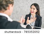 Boss/Business man employer admires young Asian business woman/staff/employee by thumb up and hands clap with smiling face for her success and good/best in work and recognition/appreciate.