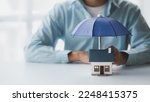 Small photo of Individuals holding small umbrellas and model homes, housing insurance against impending loss and fire, building fire insurance, home and real estate insurance concepts.