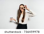 a beautiful girl in a blouse and wearing glasses holds 2 coins in her hands, and one of the coins framed her to the eye. Bitcoins, crypto currency