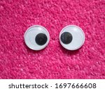 Small photo of Funny Wiggle Google Eyes on Fabric Silly Pink Fur Carpet Background
