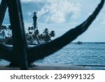 Small photo of Oceanic Elegance: Breathtaking Lighthouse, Palms and Lone Boat Adrift