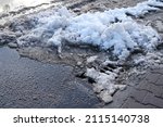 Small photo of part of street in city, drainage runoff, pavement after heavy snowfall, wet snow melts, slush and mud impede movement of pedestrians and vehicles, concept traffic safety, work of public utilities