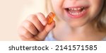 Small photo of small child, blonde girl 3 years old wants to eat gelatinous sweets, gummy bear, kid has a good appetite, happy childhood, balanced diet, sweet life, unhealthy food, halal food