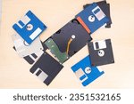 Small photo of vintage retro electronic data storage devices from 80s, 90s, cd disk, flash drives, modern hard disk scattered on table. Stack of floppy disks in grey, black, blue
