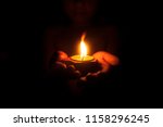 Little child holding burning candle in darkness with noise and grain effect.