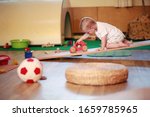 Small photo of Little boy playing independently in a playgroup with red toy car