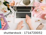 Woman work on laptop. Creative desk workspace with computer, clips, flowers, cosmetics, glasses. Flat lay style. Freelance and remote work concept