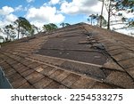 Wind damaged house roof with missing asphalt shingles after hurricane Ian in Florida. Repair of home rooftop concept