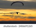 Paraglider silhouette against sunset Paragliding on Pálava hill in Czech Republic. 
