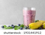 Blueberry, banana and spinach smoothie or milkshake in a glass with fresh fruits and berries. Healthy drink. close up
