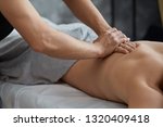 Young handsome man enjoying a back massage. Professional massage therapist is treating a male patient in apartment. Relaxation, beauty, body and face treatment concept. Home massage.