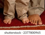 Small photo of heartwarming and symbolic image of a little girl feet and dady´s bigfoot