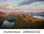 Amazing sunset over calm waters of Norwegian nortern fjords, Ersfjorden and Bergsfjorden, and small town tucked away among hills. Viewpoint from Husfjellet, Senja island. Tourism, travel concept. 