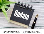 UPDATE text with decorative flower, fountain pen and notepad on wooden background. Business concept