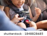 Parent buckling her child's seat belt in the car. Transportation safety.