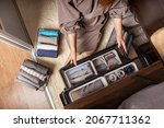 Small photo of Housewife hands with neatly put underwear, clothes and accessories modern wardrobe organization top view. Woman arms carrying ecological minimalist clothing box container storage Marie Kondo method
