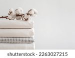 Small photo of Cotton branch with pile of neatly folded bed sheets, blankets and towels. Production of natural textile fibers. Manufacture. Organic product.