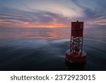 Small photo of Bell buoy floating on a calm ocean with a pastel sunset