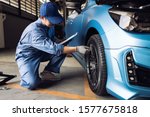 Maintenance male checking tire service via insurance system at garage, Safety vehicle to reduce accidents before a long travel, Blue car of man transportation lifestyle  