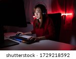 Pro player gamer young asian woman playing online video game shooting fps tournament ranking cyber internet at night red neon light room with gaming headset and keyboard on championship event.