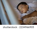 Small photo of An Asian Chinese 1-2 yeas old kid lying on medical bed on bed rest after operation