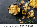 Bowl of home made potato chips served with mustard, rosemary, fleur de sel salt on stone background. Top view. Copy space