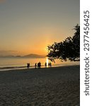 Small photo of At Hong Kong's Pui O Beach, a leisurely sunset paints the sky. Several silhouettes revel in the beauty before hurrying back to camp, preparing for a delicious feast.