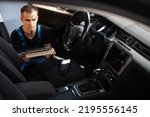 Professional car mechanic repair service and checking car engine by diagnostics software on tablet computer. Expertise mechanic working in automobile repair garage.