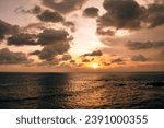 Small photo of A fiery sunset illuminates the sky over the ocean in Sri Lanka. The clouds are ablaze with color, from fiery reds and oranges to brilliant yellows and pinks. The ocean reflects the colors of the sky.