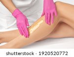 A beautician makes a sugar paste depilation of a woman's legs in a beauty salon. Female aesthetic cosmetology.