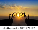 Silhouette of happy teamwork standing and touch 2021 text on beautiful sunrise backgroud celebrate business success and growth to year 2021.