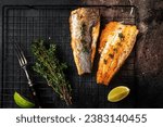 Grilled sea bass fillet with lime and thyme. Black background. Top view.