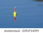 Small photo of Angler's fishing bobber float in calm lake pond reflection in the Chippewa National Forest, northern Minnesota USA