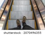 Male feet on the escalator, top view.
