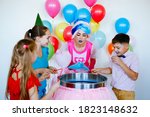 Children's birthday party. Teenagers in caps and a fairy woman make candy floss.