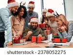 New Year's and Christmas mood. Group of business people in Santa hats, colleagues unpacking gifts at work in the office.