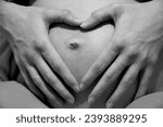 Small photo of Pregnant woman's belly and hands clasped in the shape of a heart