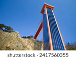 Small photo of Samcheok City, South Korea - December 28, 2023: Majestic view of a tall elevator tower against a clear blue sky, ascending the sheer hillside to Lady Suro Memorial Park.