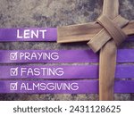 Small photo of Christianity concept about Ash Wednesday, Good Friday, Lent Season and Holy Week. LENT, PRAYING, FASTING and ALMSGIVING written on purple ribbons. With blurred background.
