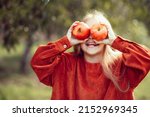 Small photo of portrait of girl eating red organic apple outdoor. Harvest Concept. Child picking apples on farm in autumn. Children and Ecology. Healthy nutrition Garden Food. Girl holding in front of her face apple