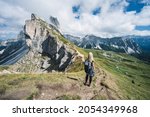 Women hiker on hiking trail path and epic landscape of Seceda peak in Dolomites Alps, Odle mountain range, South Tyrol, Italy, Europe