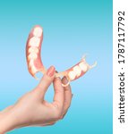 Small photo of flexible nylon denture on female hand. Removable dentures flexible, devoid of nylon, hypoallergenic exempt from monomer