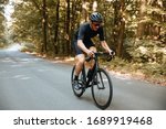 Active bearded man in sport clothing and black helmet riding bicycle  with beautiful nature around. Mature cyclist in mirrored glasses doing favorite hobby outdoors.