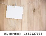 Small photo of white craft sheet with a beautiful interesting pattern on white clothespins hang on a thread on a wooden background