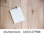 Small photo of white craft sheet with a beautiful interesting pattern on white clothespins hang on a thread on a wooden background