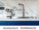 New sink and modern tap in stylish kitchen. Luxury new kitchen with marble tiled backsplash. Modern kitchen interior. Clean kitchen sink, close up.