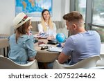 Small photo of Woman travel agent gives a couple passports with plane tickets in travel agency.