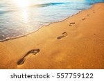 beach, wave and footprints at sunset time